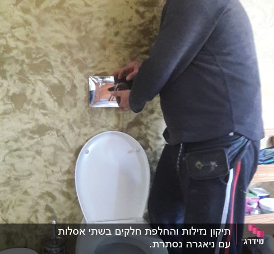אדם מתקן לחצן ניאגרה בשירותים